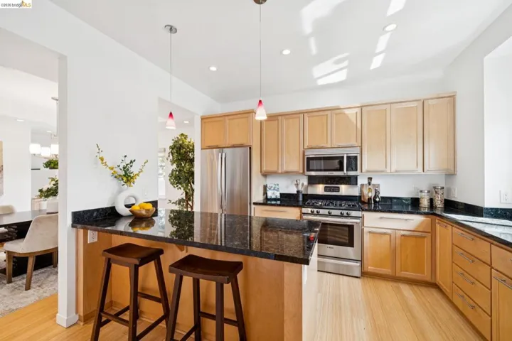 Kitchen featuring a counter-height island, stainless steel appliances, wood-finish cabinetry, and dark countertops