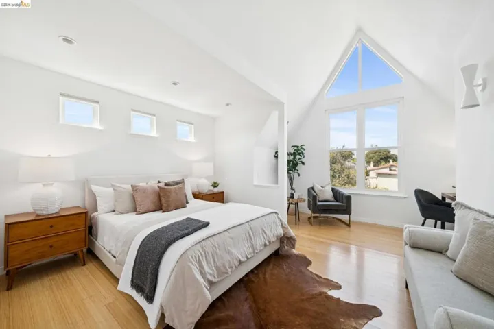 Vaulted white ceilings, wood-finish flooring, a large A-frame window, and three clerestory windows