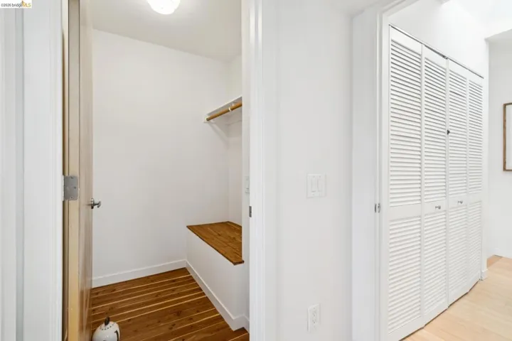 Built-in wooden bench, wood-finish flooring, and white louvered bifold closet doors