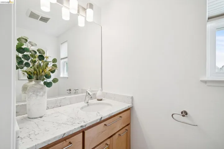 Vanity with a light-colored countertop, integrated sink, and light wood-finish cabinetry