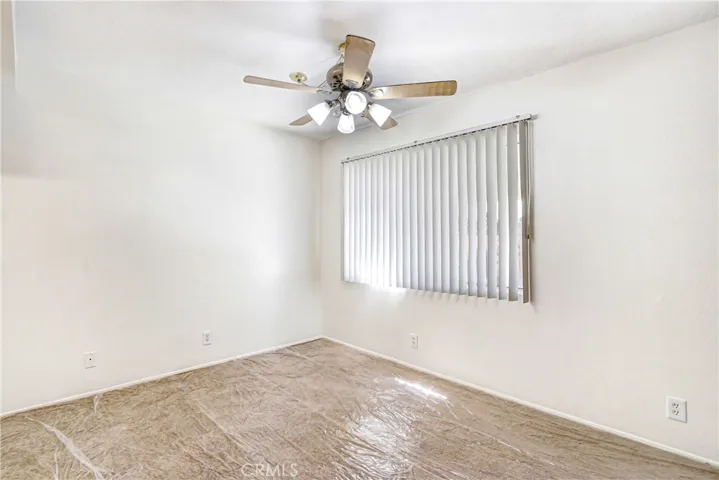 Living area with Ceiling fan and Light,  vertical blinds. Carpet with temporary carpet protector.