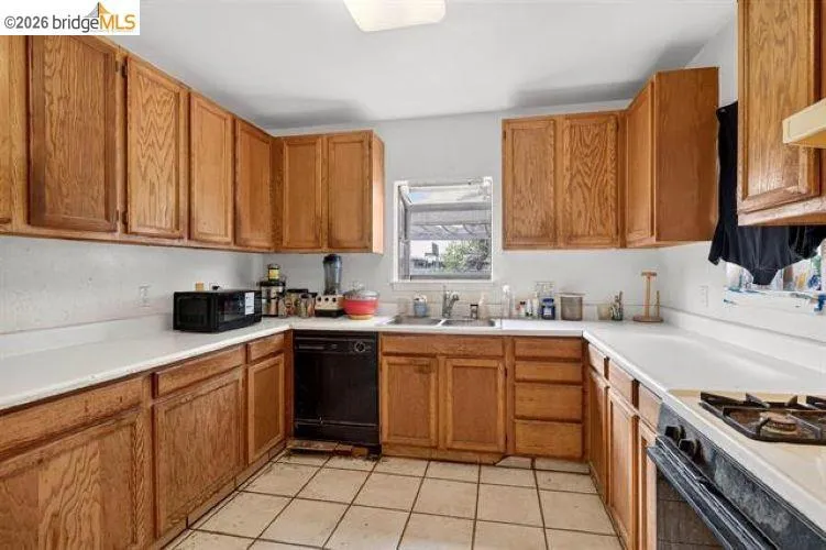 U-shaped kitchen layout with wood-finish cabinetry, white countertops, and tile flooring