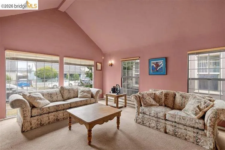 Vaulted ceiling, multiple windows, wall-to-wall carpeting, and a built-in wall sconce