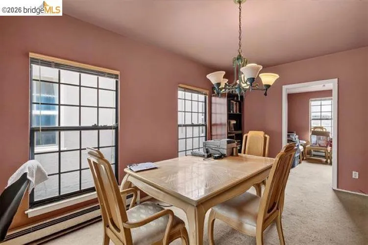 Dining area featuring grid-pattern windows, a multi-light chandelier, and an integrated built-in bookshelf