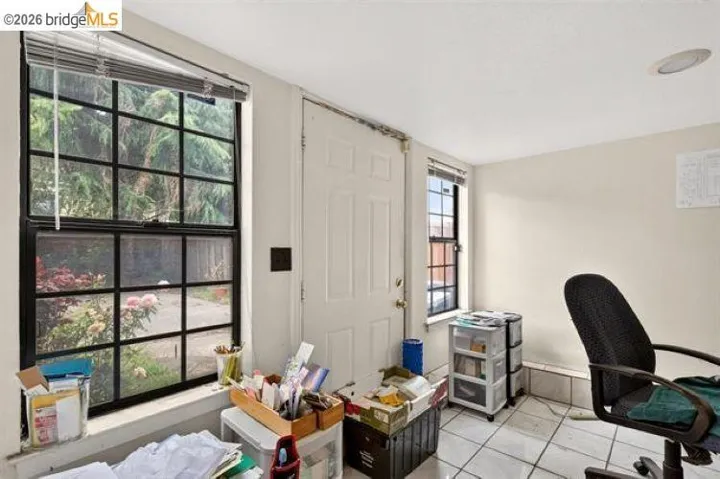 Room featuring tiled flooring, a paneled door, and two windows with black grilles