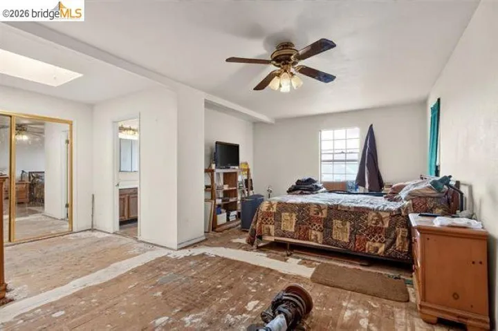 Bedroom featuring a ceiling fan, a skylight, a window, and a mirrored closet door