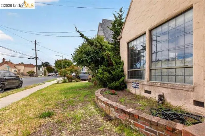 Brick facade with large gridded window and mature landscaping featuring evergreen plantings and manicured lawn