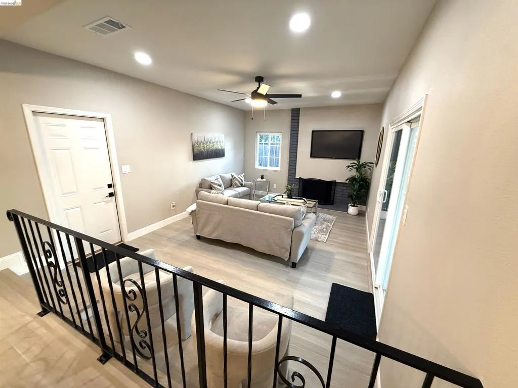 Recessed ceiling lighting, wood-finish flooring, ceiling fan, fireplace with a brick surround, and sliding glass door Recessed ceiling lighting, wood-finish flooring, ceiling fan, fireplace with a brick surround, and sliding glass door
