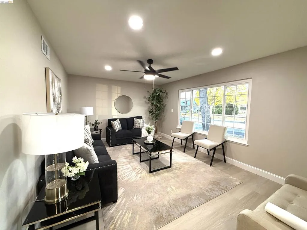 Light wood-finish flooring, recessed lighting, ceiling fan, and large picture window with grid detailing Light wood-finish flooring, recessed lighting, ceiling fan, and large picture window with grid detailing