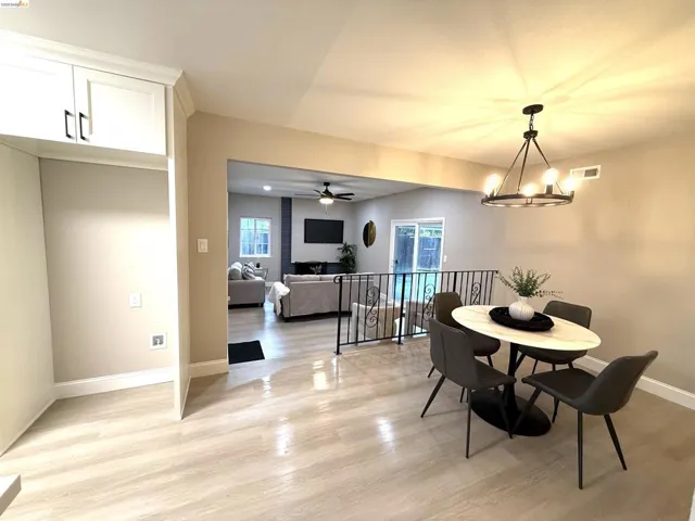 Recessed lighting, wood-finish flooring, white cabinetry with dark hardware, wrought iron railing, and a ceiling fan