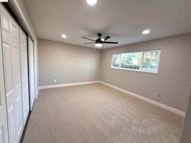 Carpeted flooring, white trim, recessed lighting, ceiling fan, and sliding closet doors