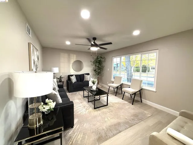 Light wood-finish flooring, recessed lighting, ceiling fan, and large picture window with grid detailing