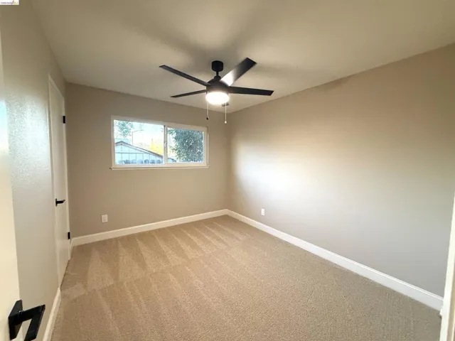 Neutral-toned walls, plush carpet flooring, and a contemporary ceiling fan with integrated lighting