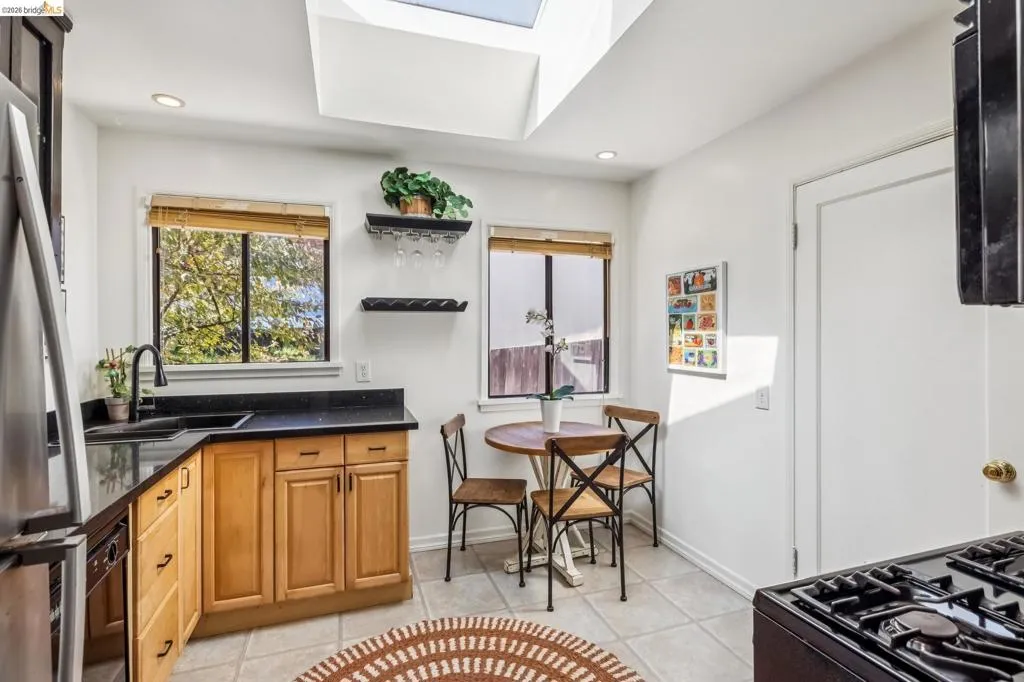 Kitchen featuring wood-finish cabinetry, dark countertops, a skylight, and recessed lighting Kitchen featuring wood-finish cabinetry, dark countertops, a skylight, and recessed lighting