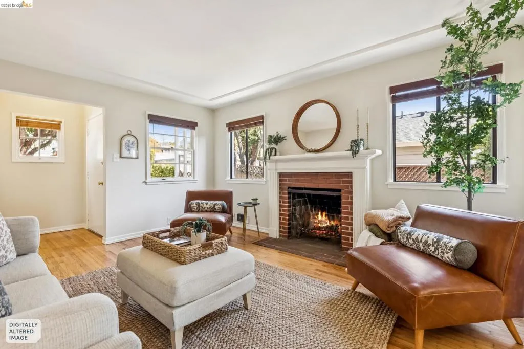 Living area featuring wood-finish flooring, a brick fireplace with a white mantel, and multiple windows Living area featuring wood-finish flooring, a brick fireplace with a white mantel, and multiple windows
