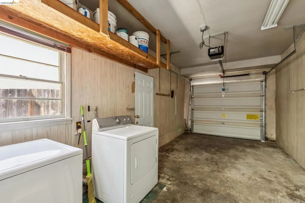Concrete flooring, overhead storage shelving, interior access door, window, and garage door Concrete flooring, overhead storage shelving, interior access door, window, and garage door