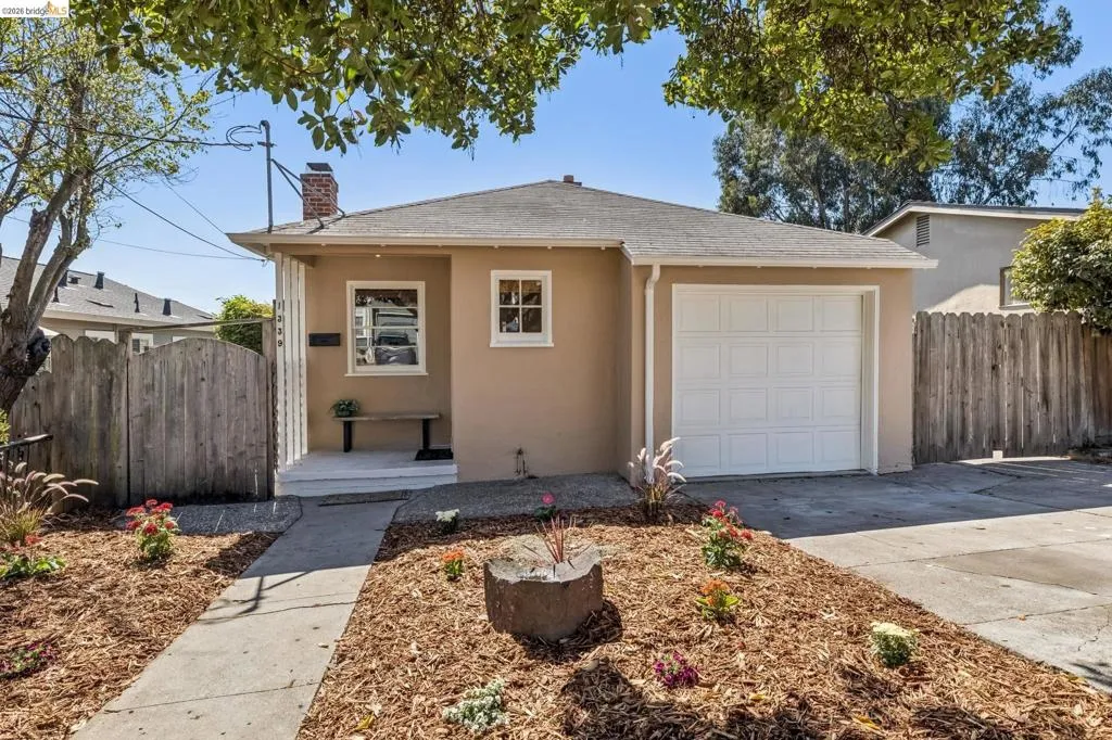 Single-story exterior with a neutral stucco finish, an attached garage with a panel door, a front porch, and a fenced yard Single-story exterior with a neutral stucco finish, an attached garage with a panel door, a front porch, and a fenced yard