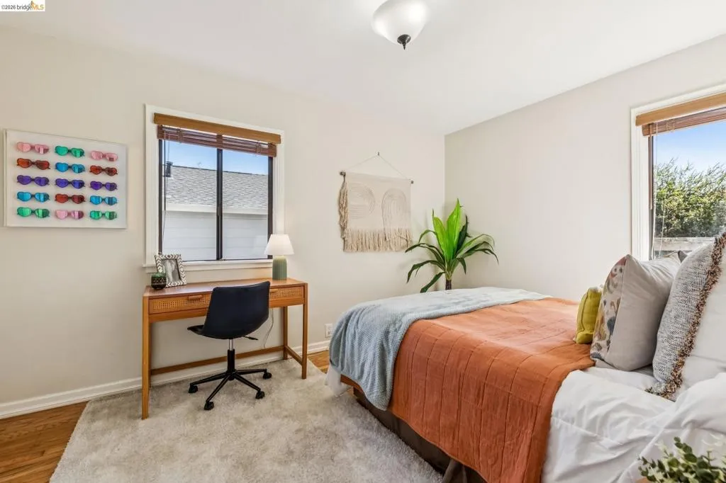 Wood-finish flooring with white baseboards, recessed window with blinds, and ceiling-mounted light fixture Wood-finish flooring with white baseboards, recessed window with blinds, and ceiling-mounted light fixture