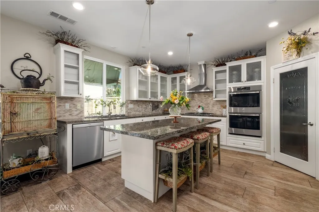 Chefs kitchen with double ovens, stainless steel appliances and walk in pantry.
