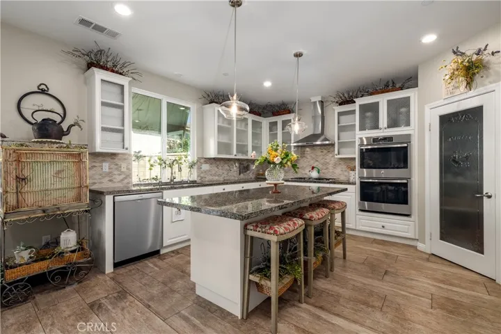 Chefs kitchen with double ovens, stainless steel appliances and walk in pantry.