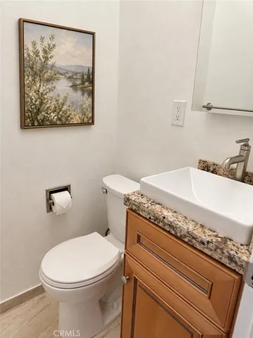 Remodeled half bathroom with granite counter top -- picture on wall was virtually placed.
