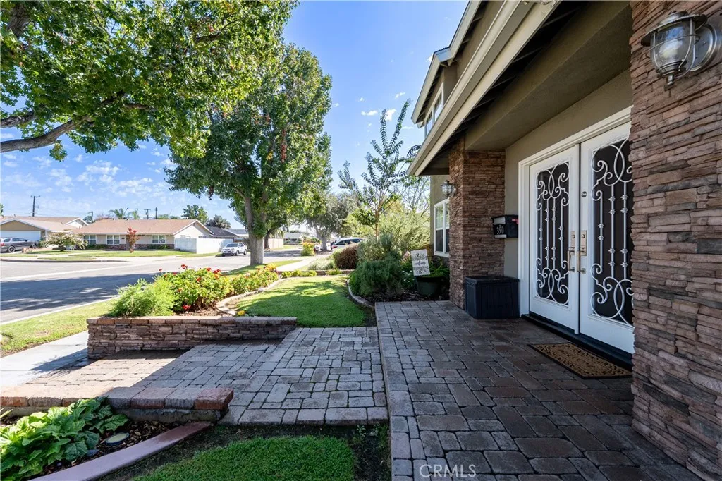 Beautifully professionally landscaped front yard with Stone pavers, mature trees, and custom stacked stone columns.