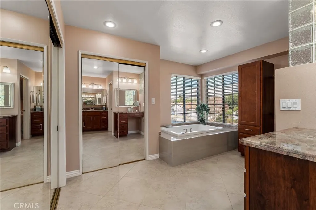 In suite, bathroom consist of granite countertops, soaking tub, mirror, wardrobes, tile floors, and separate toilet room.