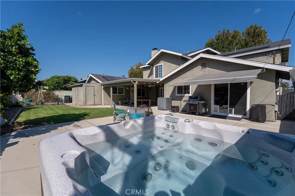 Large back yard with concrete patio area, grass, shed area, garden area and relaxing spa.