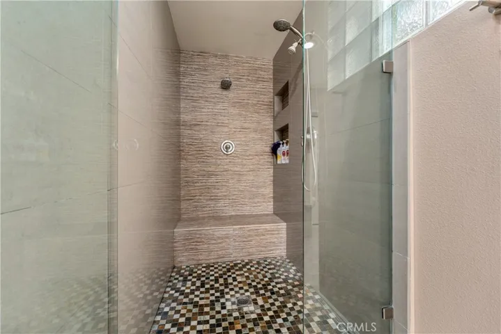 primary en suite bathroom has a custom oversized shower with multiple rain heads.