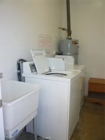 Inside the community laundry room with one washer and one dryer plus a utility sink.