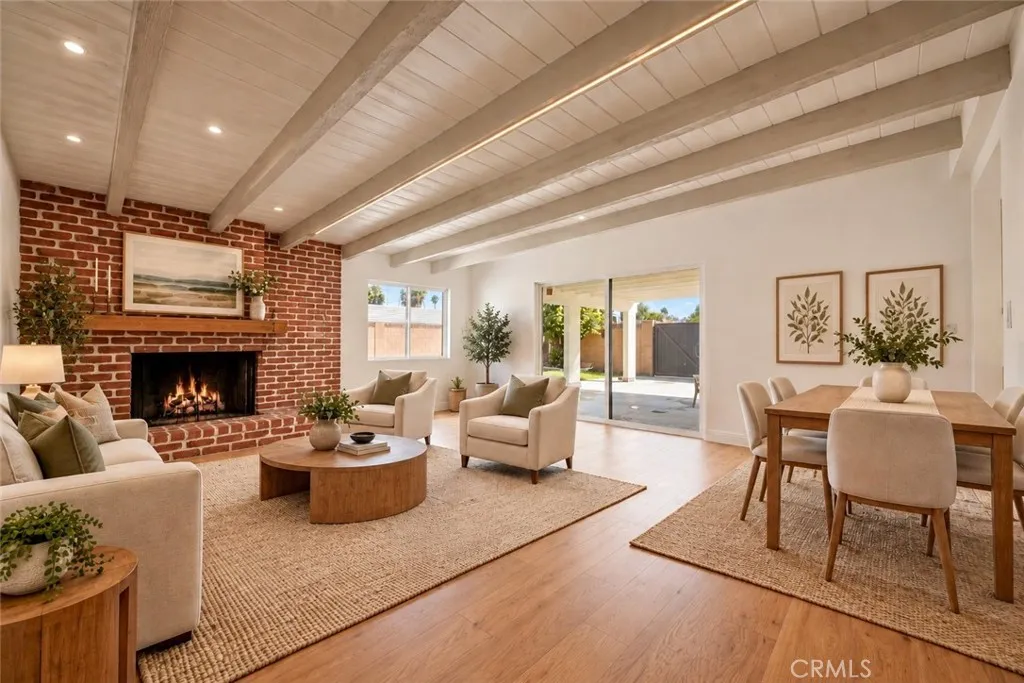 The adjoining family room offers a beamed ceiling and striking floor-to-ceiling brick fireplace with raised hearth. A dining area and sliding glass door opening to the covered rear patio make this an inviting space for everyday living and entertaining. Photo is virtually staged. The adjoining family room offers a beamed ceiling and striking floor-to-ceiling brick fireplace with raised hearth. A dining area and sliding glass door opening to the covered rear patio make this an inviting space for everyday living and entertaining. Photo is virtually staged.