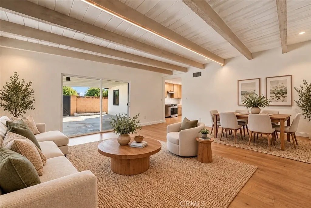 The adjoining family room offers a beamed ceiling and striking floor-to-ceiling brick fireplace with raised hearth. A dining area and sliding glass door opening to the covered rear patio make this an inviting space for everyday living and entertaining. Photo is virtually staged. The adjoining family room offers a beamed ceiling and striking floor-to-ceiling brick fireplace with raised hearth. A dining area and sliding glass door opening to the covered rear patio make this an inviting space for everyday living and entertaining. Photo is virtually staged.