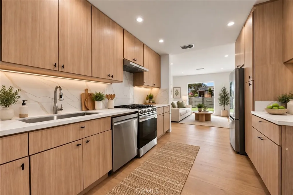 The remodeled kitchen features contemporary soft-close cabinetry, stone countertops, stainless steel refrigerator, gas range and dishwasher, an undermount sink, and pantry storage. Photo is virtually staged. The remodeled kitchen features contemporary soft-close cabinetry, stone countertops, stainless steel refrigerator, gas range and dishwasher, an undermount sink, and pantry storage. Photo is virtually staged.