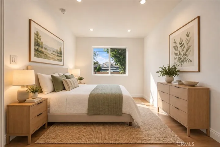 The primary suite features a walk-in closet and remodeled private bath with mosaic tile flooring, floating vanity, designer lighting, and custom-tiled tub/shower combination with glass panel. Photo is virtually staged.