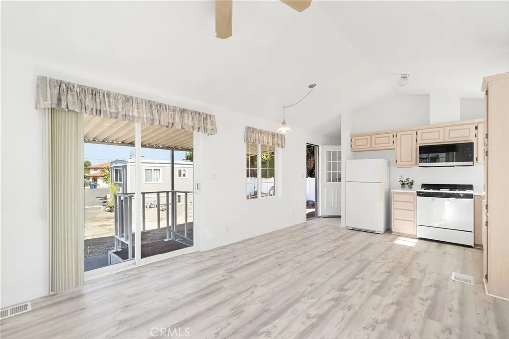Reverse living room view with partial kitchen view, sliding door and back door view.