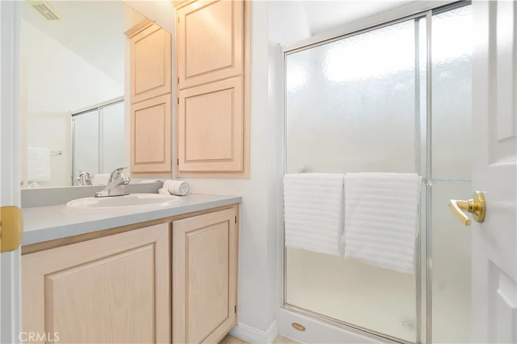 Bathroom with walk in shower, sink vanity, medicine cabinet and extra cupboards.  Bathroom has a white toilet not shown in these photos.