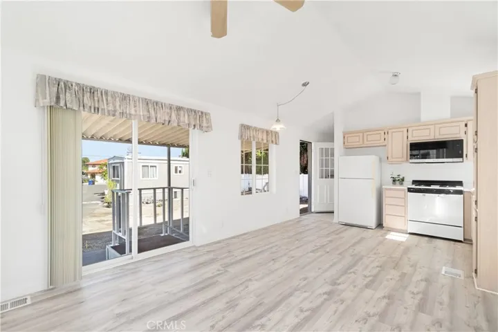 Reverse living room view with partial kitchen view, sliding door and back door view.