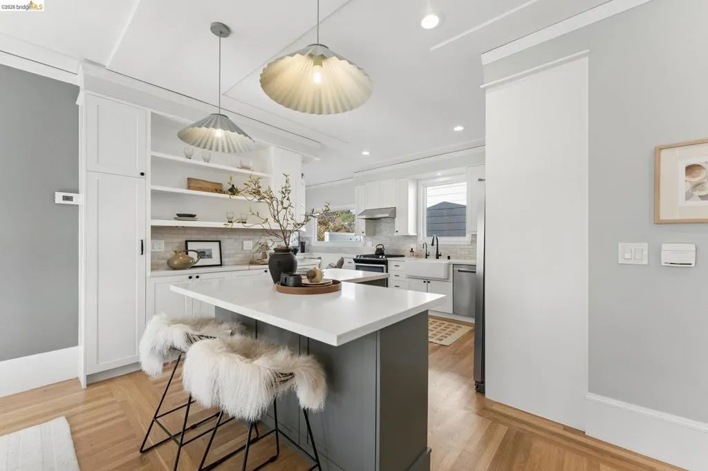 Kitchen featuring a central island with a solid surface countertop, built-in floor-to-ceiling cabinetry, open shelving, an apron-front sink, and metal pendant lighting