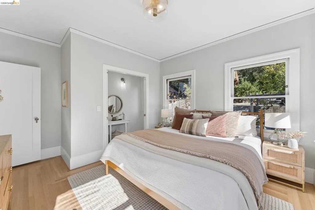 Neutral-toned interior featuring wood-finish flooring, crown molding, and two multi-pane windows with detailed casing