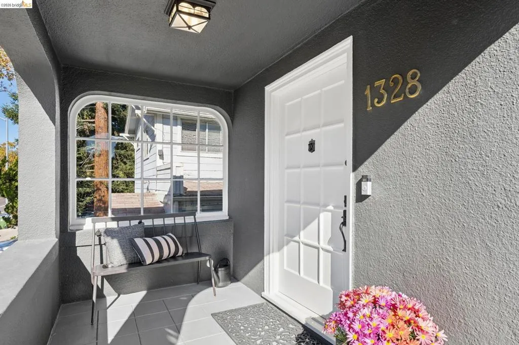 Covered entryway featuring a multi-pane door, arched window, tile flooring, and metallic house numbers