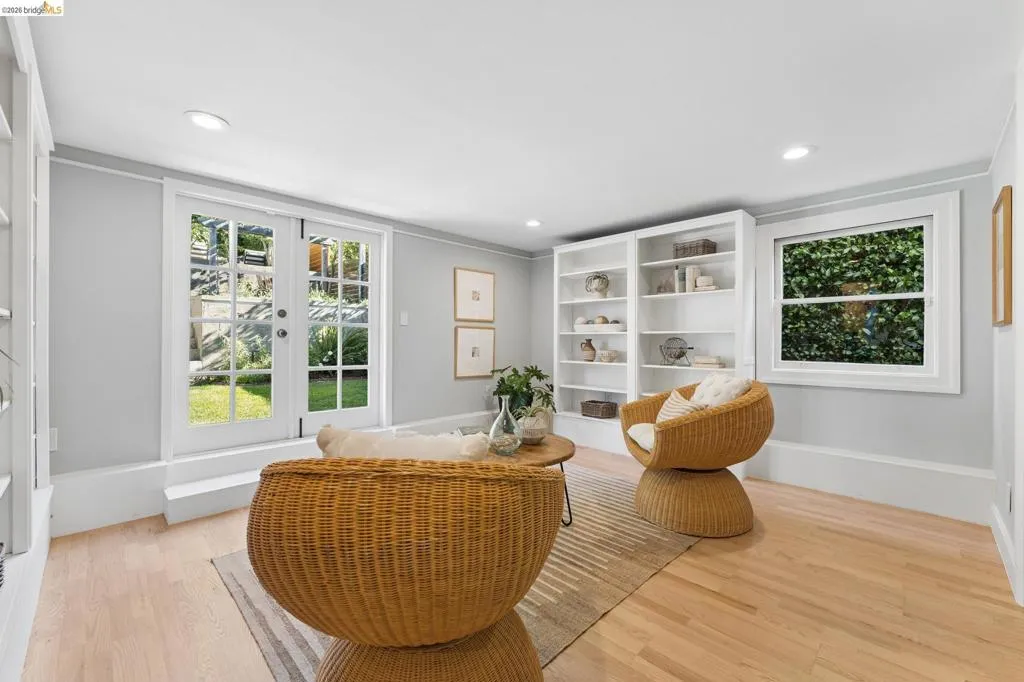 Light-filled interior featuring white built-in shelving, wood-finish flooring, recessed lighting, and glass-paned French doors opening to an outdoor area