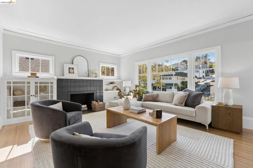 Living space featuring a large window array, charcoal tile fireplace surround, crown molding, built-in cabinetry with glass-front doors, and wood-finish flooring