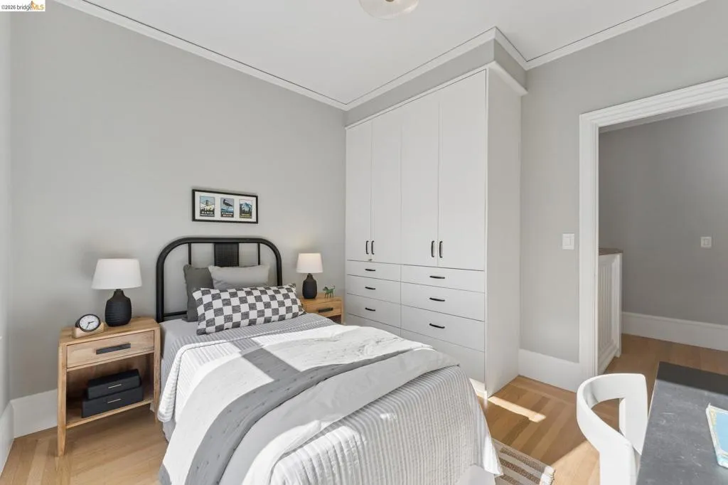 Built-in white cabinetry featuring floor-to-ceiling storage and integrated drawers with matte black hardware, paired with light-toned wood-finish flooring