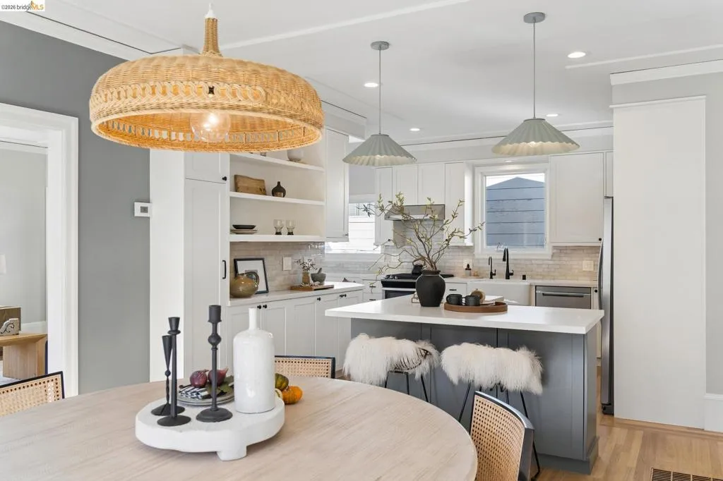 Kitchen featuring custom shaker-style cabinetry, a central island with a quartz countertop, built-in open shelving, decorative woven and metal pendant lighting, and wood-finish flooring