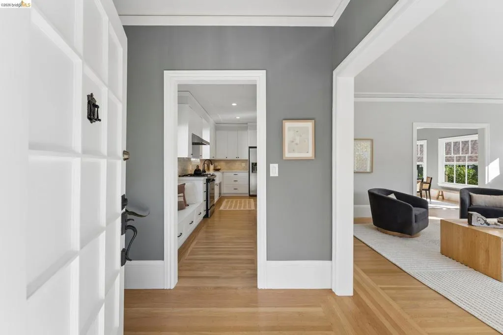 Entryway featuring hardwood flooring, wide door casings, crown molding, and high-contrast interior paint