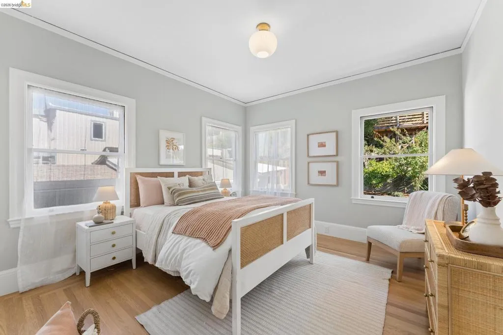 Room featuring wood-finish flooring, multi-pane windows with thick white casing, crown molding, and a spherical glass flush-mount light fixture