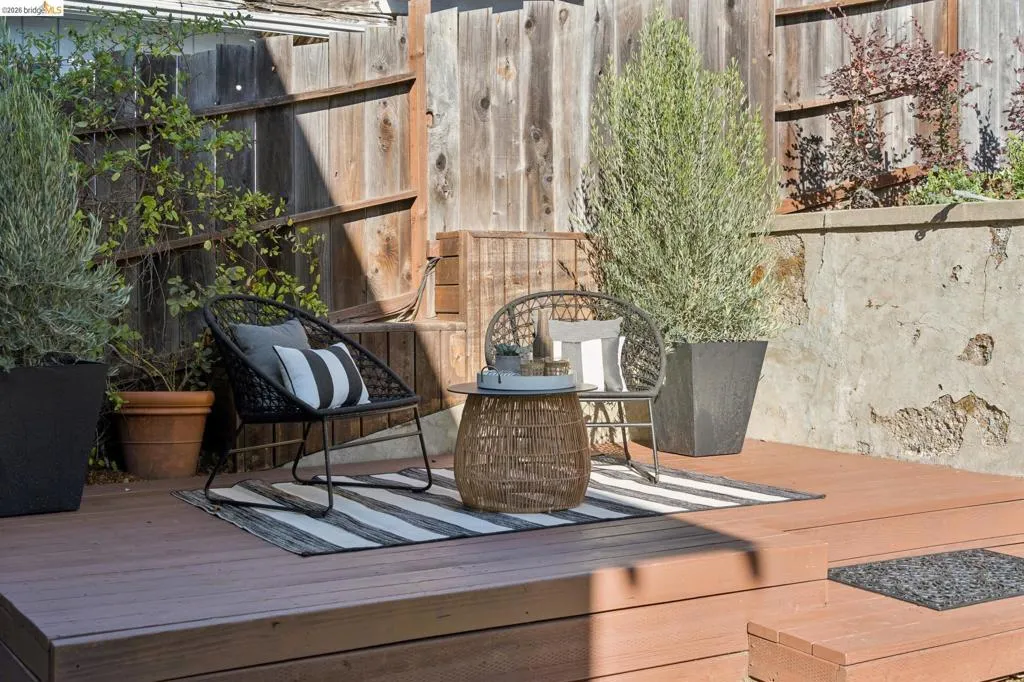 Tiered wood-finish decking featuring a stone retaining wall and wood privacy fencing