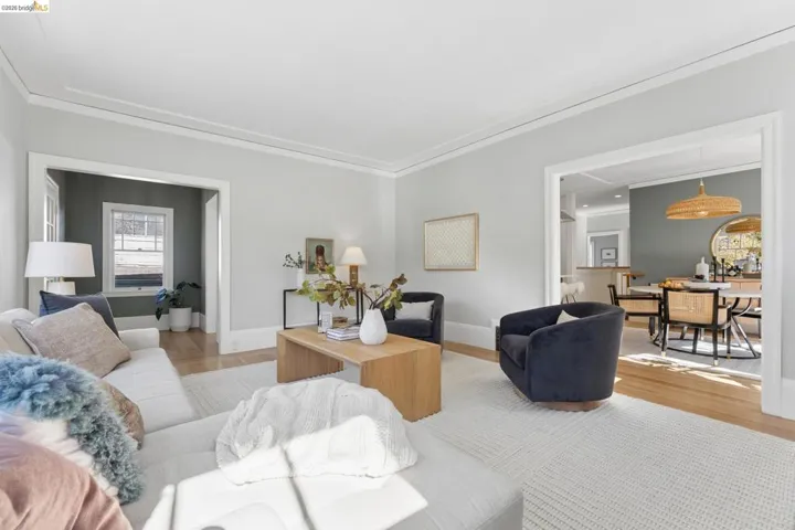 Living area featuring neutral wall paint, crown molding, wide door casings, and wood-finish flooring
