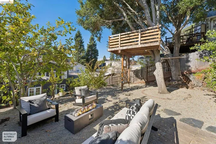 Outdoor space featuring a gravel ground surface, mature trees, wood-construction elevated platform, and wooden fencing