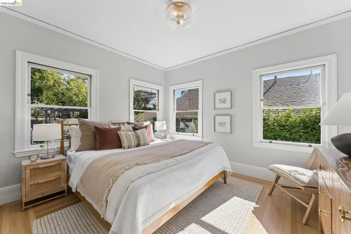 Bright room featuring wood-finish flooring, multi-pane windows, crown molding, and a dome-style flush mount ceiling light fixture